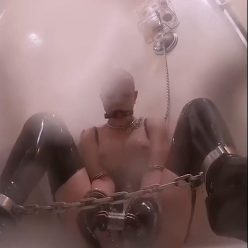 Latex Bondage – Latex Shower – Gagged, belted, and shackled Rachel Greyhound is chained to the shower rack - Sexy Latex
